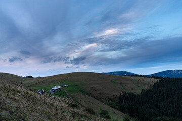 Morning landscape in the mountains. Dawn in the mountains. Rural huts on top of the mountain. Cloudy sky over the village.