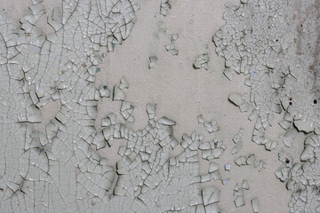 Peeling paint on the wall. Old concrete wall with cracked flaking paint. Weathered rough painted surface with patterns of cracks and peeling. High resolution texture for background and design. Closeup