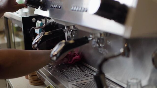Barista cleaning portafilter on coffee machine by trun on steaming. Barista cleaning steaming coffee machine in daily use by streaming pressure in coffee shop