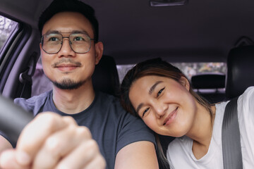 Asian Thai couple smiling happy time while driving a car on road, enjoy vacation holiday. front view.
