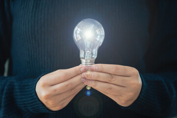 Woman holding a light bulb in her hand.