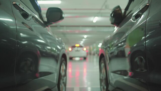 Modern underground city parking with unrecognizable moving cars, focusing on the foreground 4K