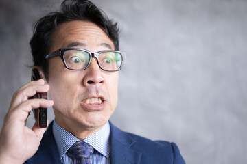 スマホで通話する男性　内容を聞いてびっくりする驚愕の表情のアップ　投資失敗など
