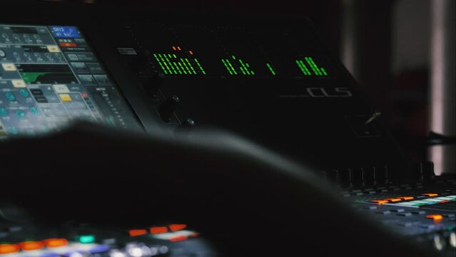 EQ volume tracks running on the sound mixer console. Close-up of a professional modern audio mixer. The hand of a music producer controlling the sound. Recording studio