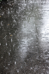 city pavement during heavy rain with raindrops splashes on water surface
