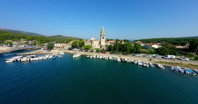 Drone soars swooping FPV through sailboat masts over town city center of Osor Croatia