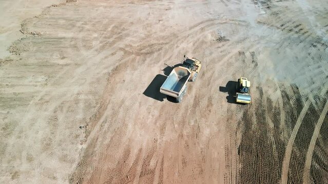 A many bulldozer levels a plot of land for construction development. Drone top down wide footage.