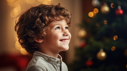 Kleiner Junge schaut lächelnd verträumt hinauf zum festlichen Weihnachtsbaum mit Bokeh-Effekt und Platz für Text - obrazy, fototapety, plakaty