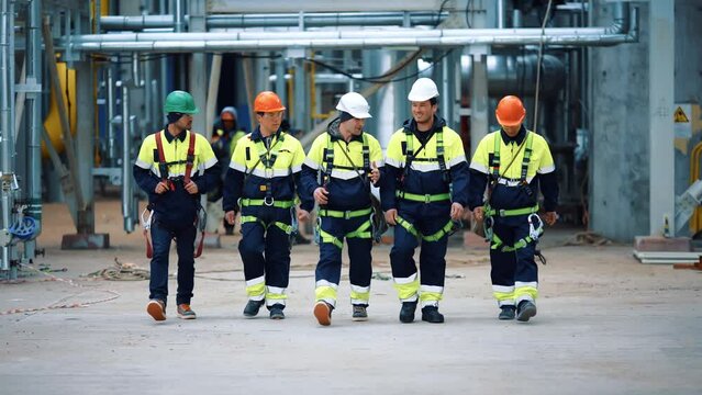 Group of Asian metalworkers in protective helmet uniform going at refinery contemporary factory