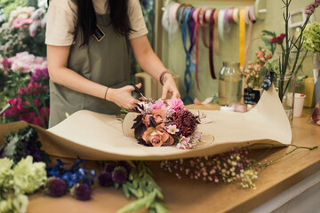 Naklejka na ściany i meble young woman florist making bouquet fresh flowers, flower shop business, no face