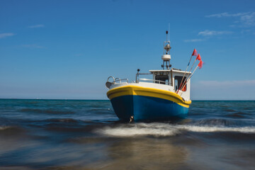 Obraz premium Fishing boat on the beach in Sopot, Poland. Magnificent long exposure calm Baltic Sea. Wallpaper defocused waves. Fishermans sea bay Vacation and holidays. travel attraction tourist destination 