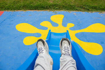 feet in white shoes falling down a slider in a park