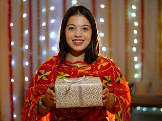 A beautiful young female happily smiling and showing a gift - Diwali festival  Indian ritual . An...