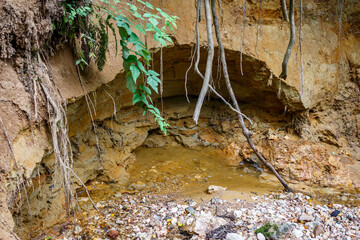 The flow of water erodes the sand layer on the shore