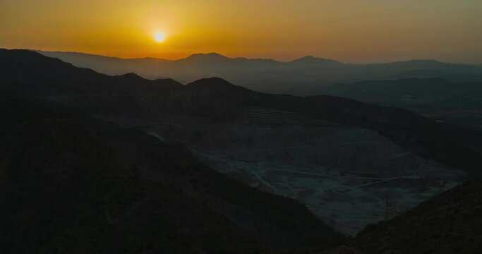 Full sunset timelapse overlooking mountain mining excavation site.