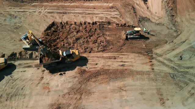 Aerial top down footage. A many bulldozer levels a plot of land for development