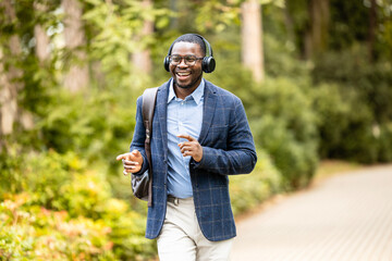 Happy man with headphones listening to music, singing and dancing while walking.