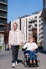 young man walking through the city with a woman using a electric wheelchair while they chatting happy, concept of friendship and diversity