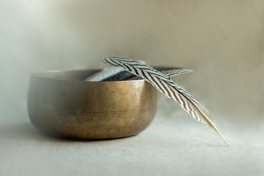 Close up of sacret eagle smudge feather by a hand made tibetan singing bowl on a natural linen background