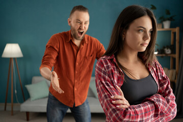 Nervous aggressive husband yelling at wife in living room. Concept of quarrel and domestic violence