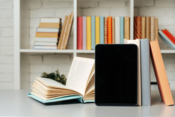 Digital tablet with stacked books in library - obrazy, fototapety, plakaty
