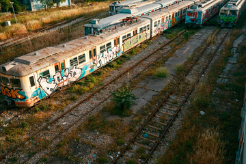 Old view of abandoned train station. Colorful graffiti on trains.