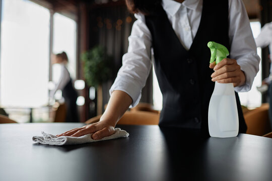 Close up of server wiping dining table in restaurant preparing for opening, copy space