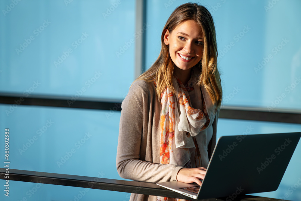 Wall mural confident young woman working on laptop while sitting near window in creative office or cafe