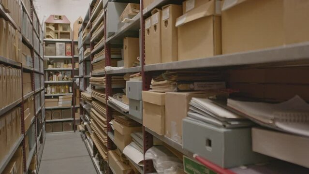 Pan over aisle of archive with cardboard boxes and files