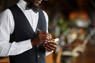 Side view cropped shot of elegant waiter holding notepad in restaurant ready to take order, copy space