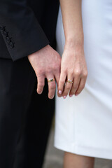 The bride and groom touch hands with wedding rings on their fingers. Love and relationships.