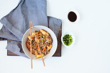 japanese food - stir fried soba noodles with chicken, carrot, baby carrots and onion served on white background