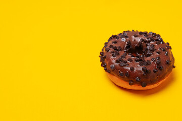Chocolate donut with chocolate chips on yellow background, space for text