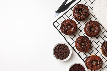 Chocolate donuts, knives and bowls on white background, space for text