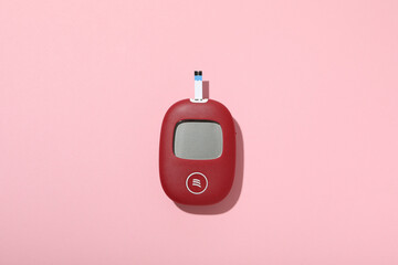 Red glucometer on pink background, top view