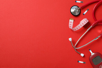 Glucometer, stethoscope and measuring tape on red background, space for text