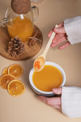 Female hands in a sweater hold a cup of sea buckthorn tea. Cozy autumn winter time