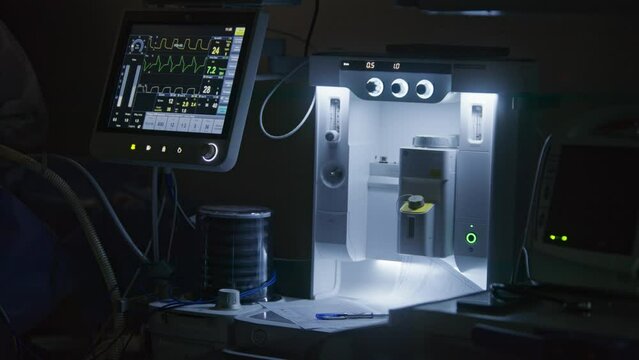 Close up shot of moving pulmoflator and monitor screen with displayed vital signs during surgery. Medical equipment in intensive care unit. Medics work in modern operating room. Emergency department.