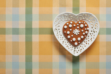 Painted gingerbread cookie in the shape of a heart on a plate in the shape of a heart