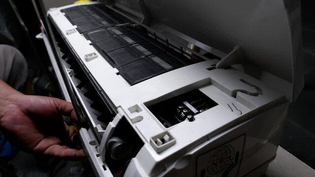 The process of disassembling a broken air conditioner by a home technician.