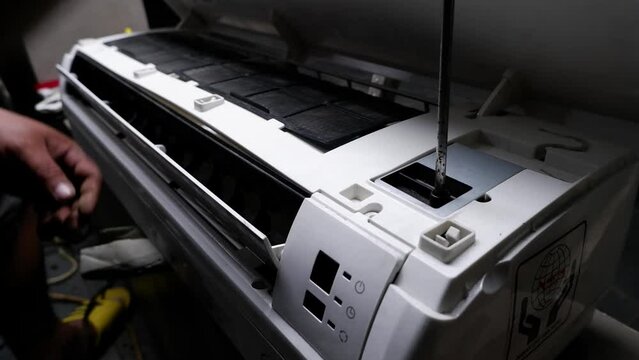 The process of disassembling a broken air conditioner by a home technician.