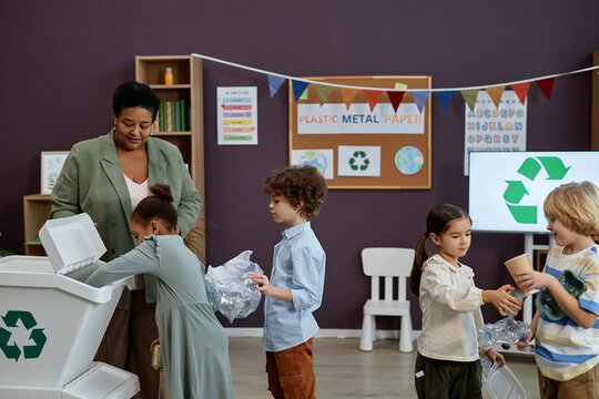Side view portrait of kids standing in line to recycling bin at waste sorting class in preschool, copy space