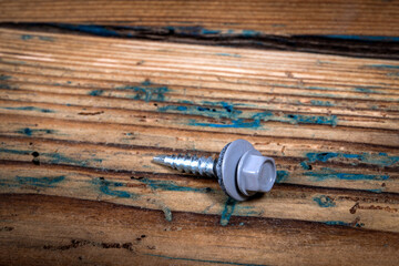 Roofing screw on a wooden texture background