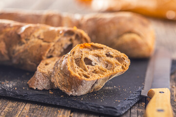 Sliced wholegrain rustical baguette on wooden table.