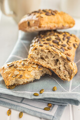 Whole grain bun with pumpkin seeds on napkin.