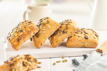 Whole grain bun with pumpkin seeds on cutting board.