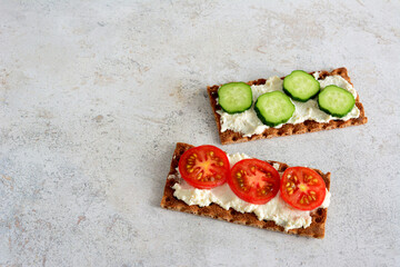 healthy snack with crispy bread, soft cheese and slices of tomato and cucumber
