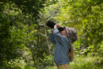 Cute little girl exploring nature looking through binoculars. Child playing outdoors. Kids travel, adventure and bird watching concept.