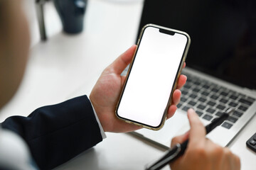 View over shoulder businessman hand holding smartphone with blank screen for apps advertising