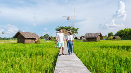 a couple of men and woman at a small homestay at the farm with a green rice paddy field in Central Thailand